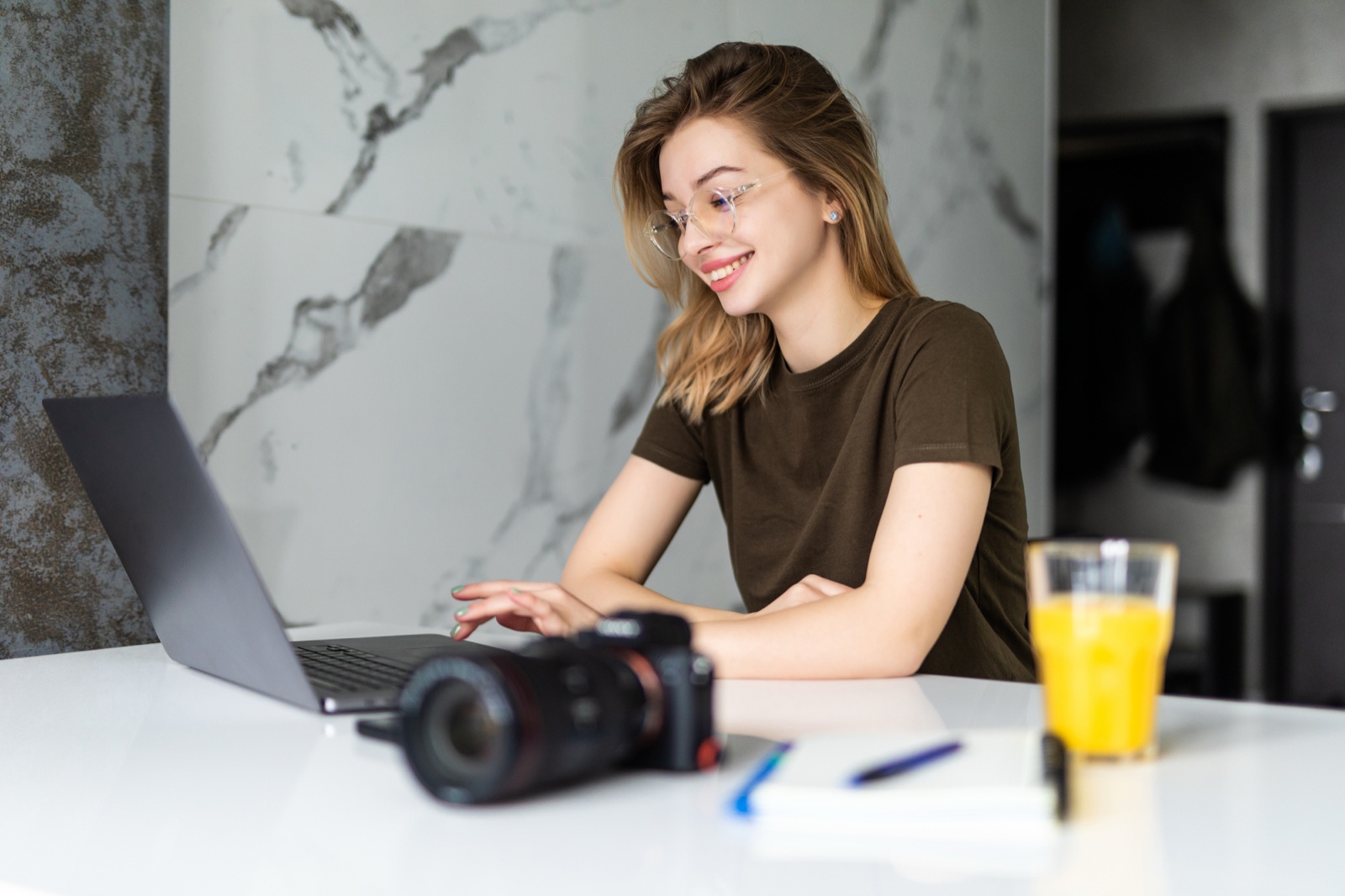 Creator working on a laptop beside a camera