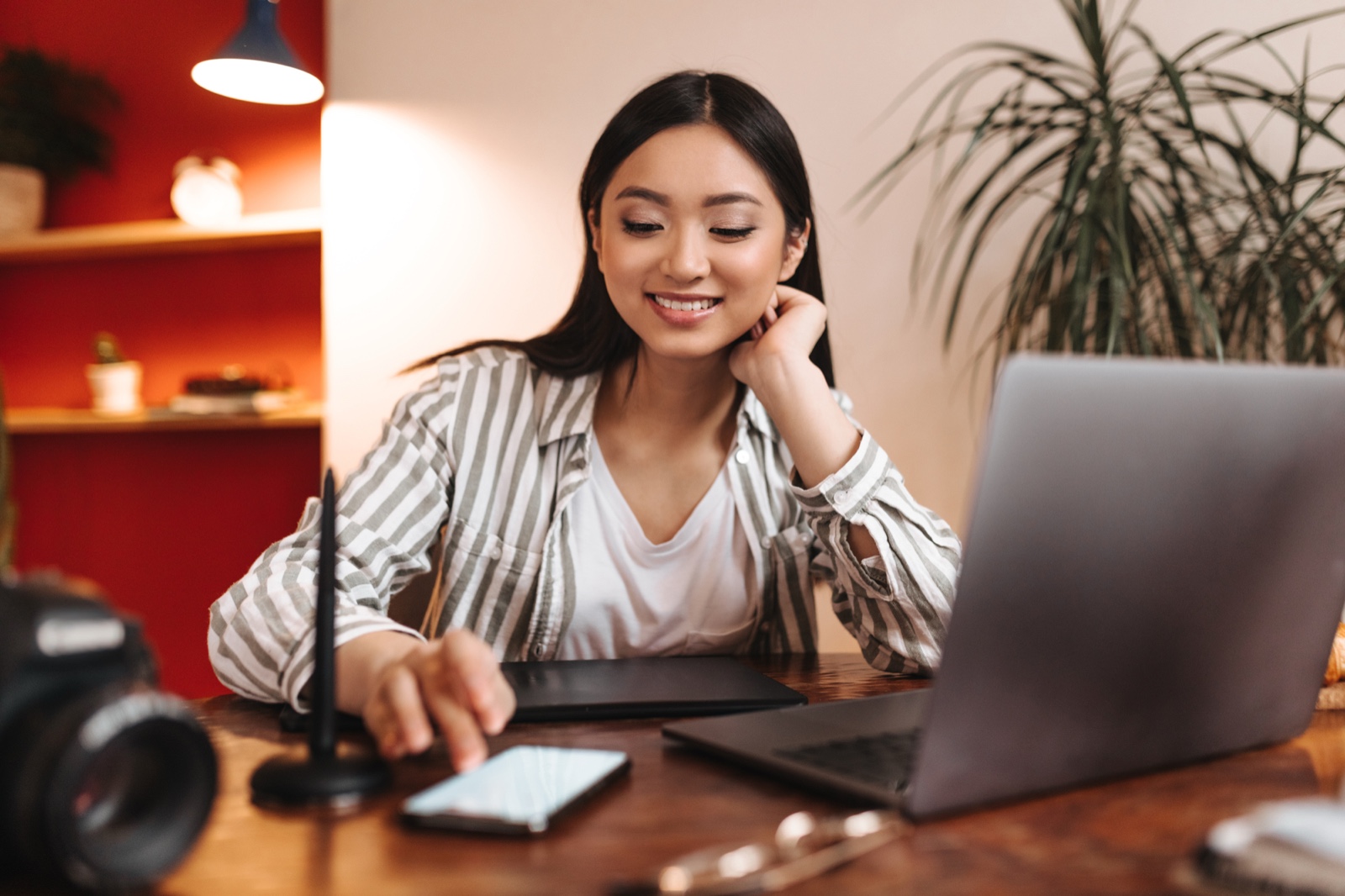 Creator using a laptop and phone at a desk