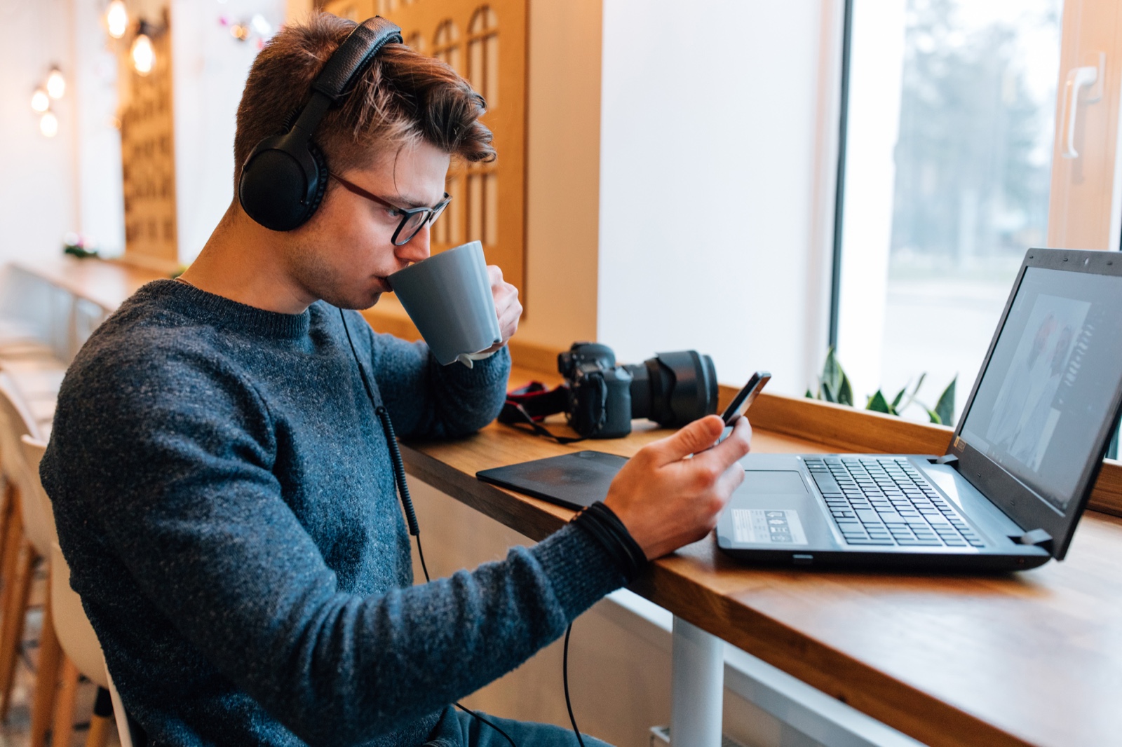 Creator checking a phone beside a laptop and camera