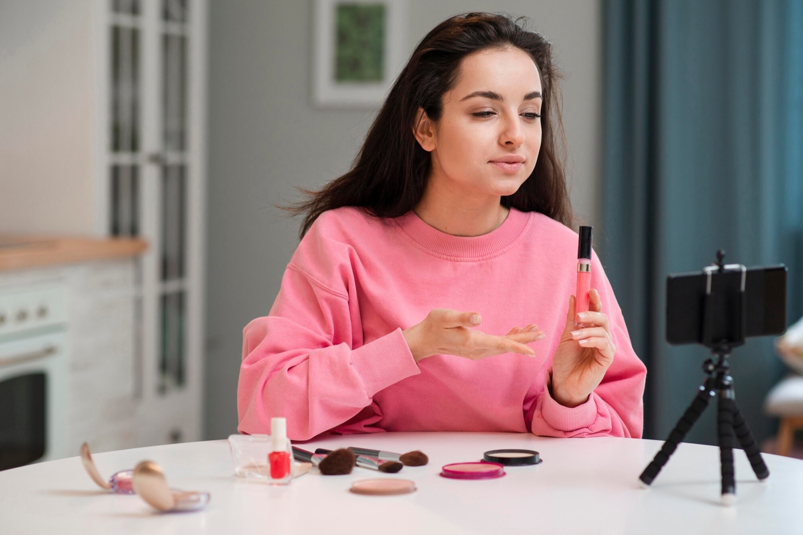 Creator showing a lip gloss to a phone on a tripod
