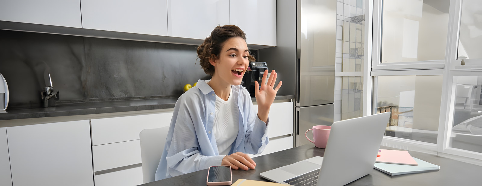 Creator waving hello on a video call from a bright home workspace