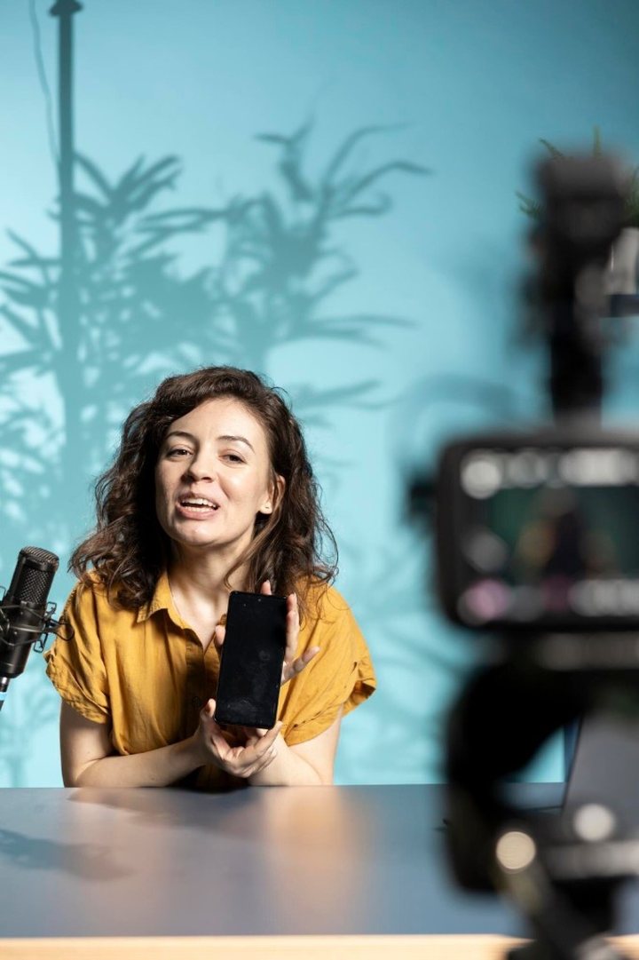 Creator holding a phone in a studio, showing Instagram on mobile