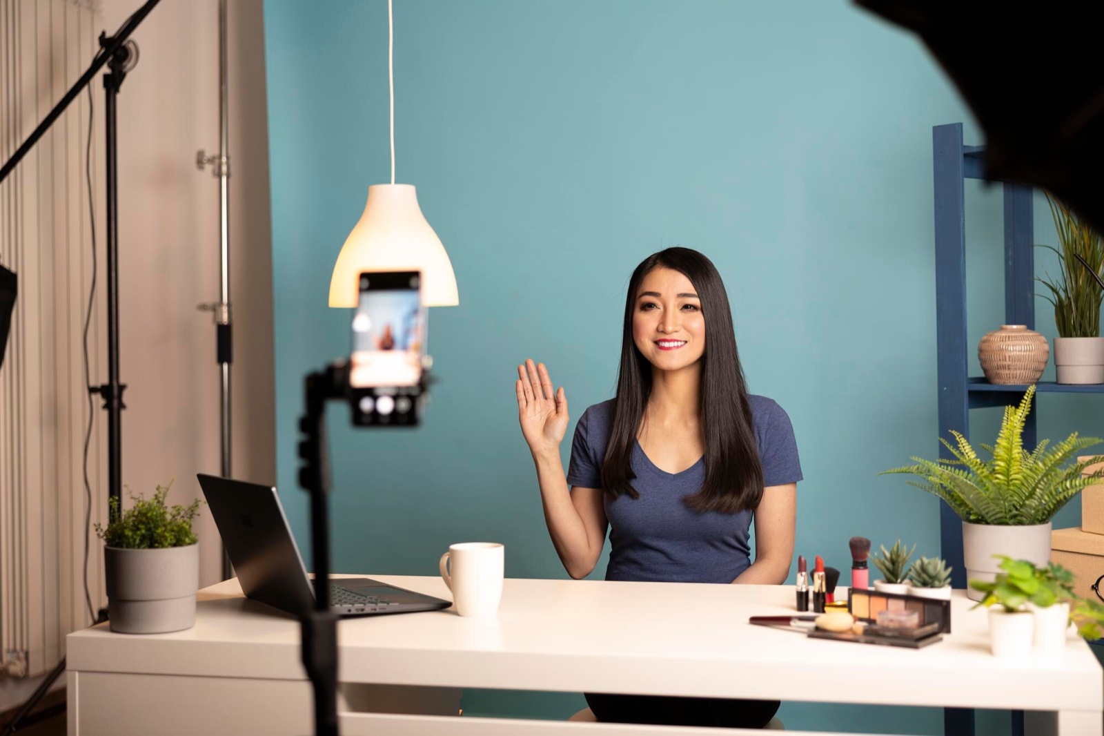 Creator waving to a camera during a desk setup