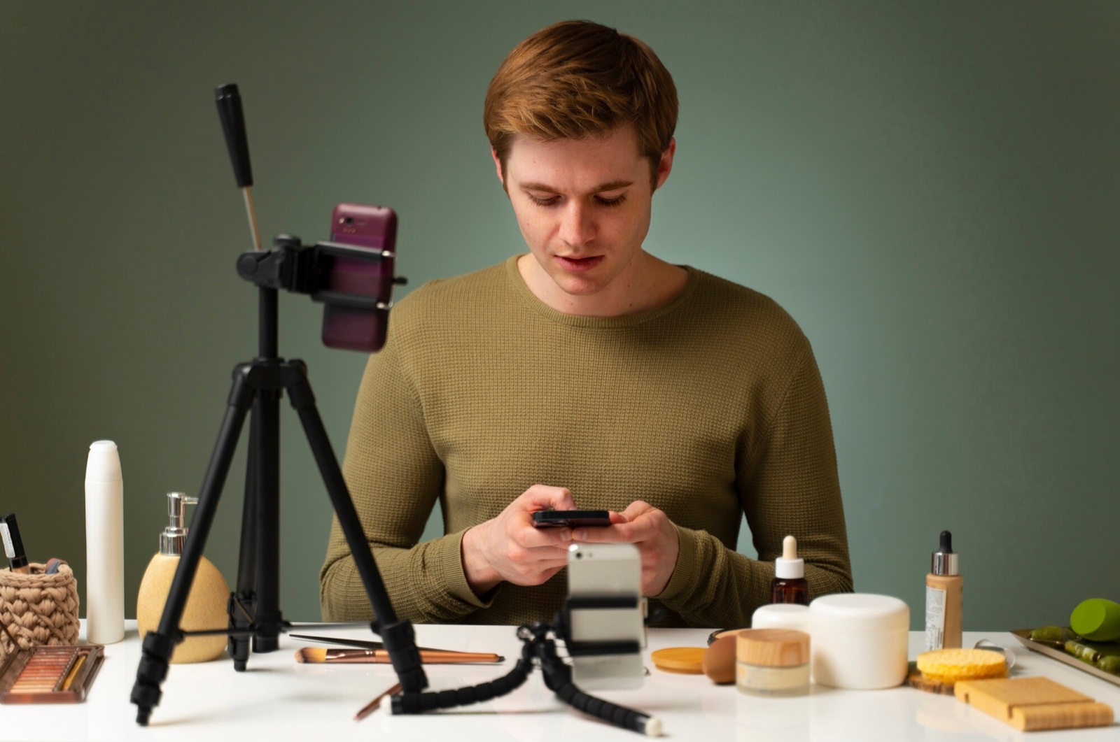 Creator looking at a phone beside skincare products